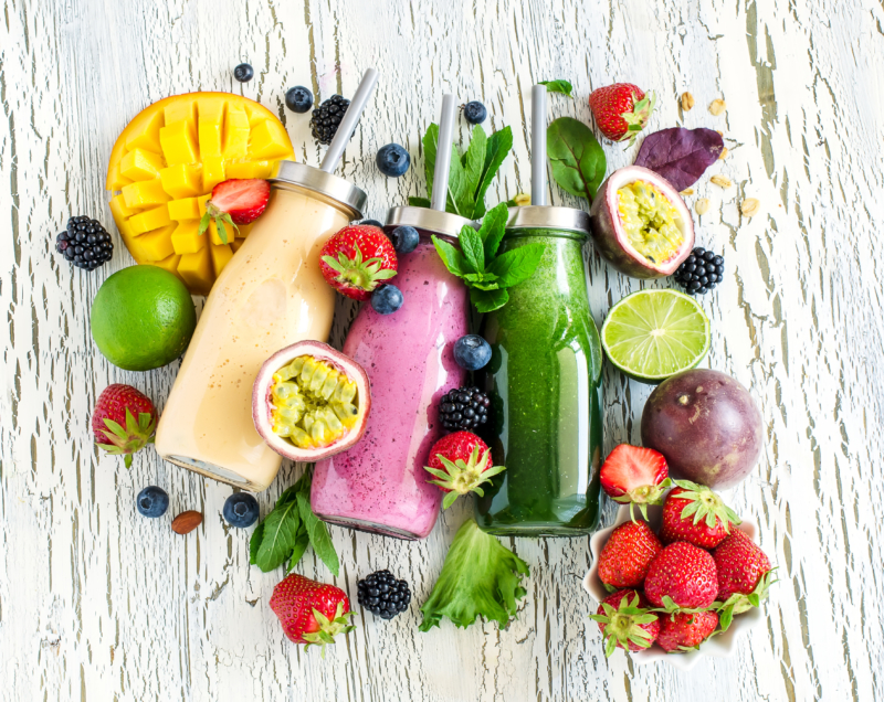 Photo de smoothies et de fruits poses sur une table, faire le plein d'énergie et de vitamine grâce a des fruits, tout au long de la journée