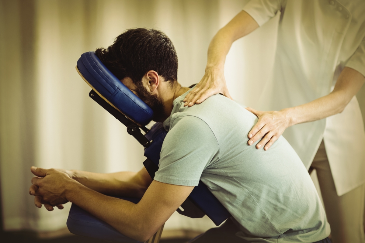 Photo d'un homme massé sur une chaise, le massage amma permet à nos collaborateurs de réduire leur niveau de stress